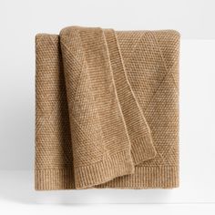 a tan blanket folded on top of a white wall