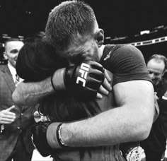 two men hugging each other in the middle of a boxing ring with people standing around