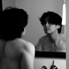 a shirtless man is looking at himself in the mirror