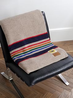 a chair with a blanket on top of it sitting on a wooden floor next to a wall