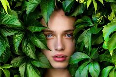 a woman's face surrounded by green leaves