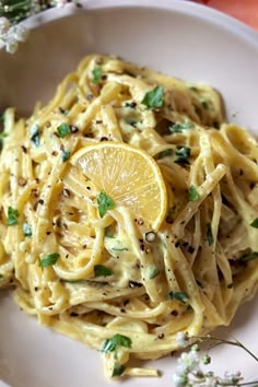 a white plate topped with pasta and lemon wedges