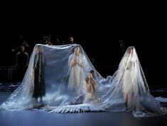 three women dressed in white veils on stage