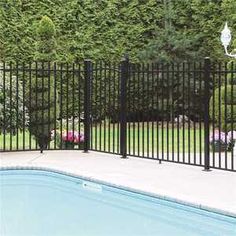 a swimming pool surrounded by black wrought iron fence and gated in area with pink flowers