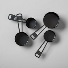 four black pans with measuring spoons and spatulas next to each other