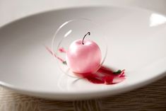 an apple in a glass bowl on a white plate with red liquid flowing down the side