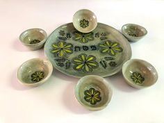 an assortment of ceramic bowls and dishes with painted flowers on the bottom, sitting on a white surface