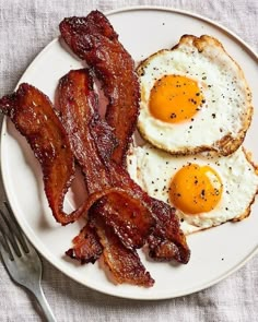 two fried eggs and bacon on a plate