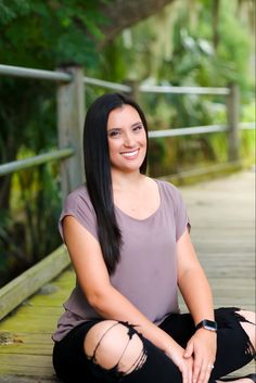 a smiling woman sitting on a wooden walkway