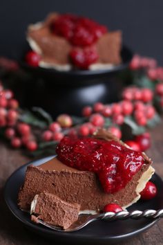 a piece of chocolate cheesecake with raspberry topping on a small black plate