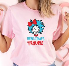 Here comes trouble Shirt, Dr Suess Trouble Thing Tee, Read across America, Kids shirt, Dr Seuss Shirt, Cat Hat, Birthday Shirt, School Shirt. IMPORTANT:  Please Review Before Placing Your Order - Ordering Process- 1- Choose your desired options from the dropdown. 2- Add to cart and finalize your purchase. 3- Ensure you include any personalization details.  - Timeframes - Processing: We prioritize processing all orders swiftly, which might range from 1 to 2 business days.      -NEXT DAY SHIPPING - - Please understand that the listed "ship date" isn't the actual "arrival date." The ship date indicates when your order departs from our location, while the delivery date signifies its arrival at your address. - SHIPPING DATE: When your package leaves our studio. - DELIVERY DATE: When your packag Dr. Seuss Shirts, Dr Seuss Shirt, Cat With Hat, Here Comes Trouble, Hat Birthday, Read Across America, School Tees, Dr Suess, Birthday Tee