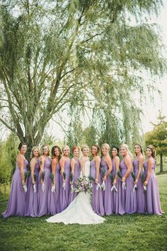 a bride and her bridal party posing for a photo in front of a tree