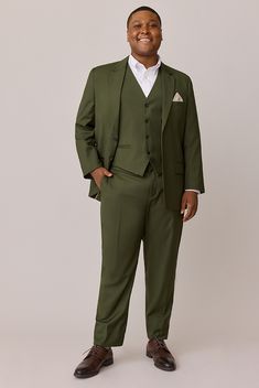 a man in a green suit and white shirt is smiling at the camera with his hands in his pockets