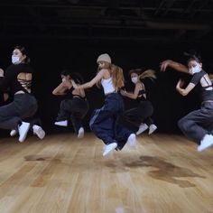 a group of young women dancing on top of a wooden floor in front of a black background