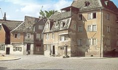 an old brick building with many windows and balconies on the top floor, in front of a cobblestone street