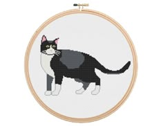 a black and white cat cross stitched into a wooden frame