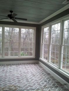 an empty room with three windows and a ceiling fan