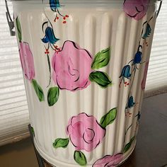 a painted flower pot sitting on top of a wooden table next to a closed window