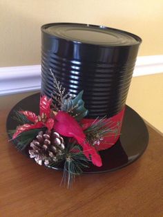 a black top hat with red ribbon and pineconis on it sitting on a table