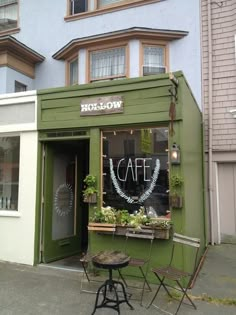 an outside cafe with tables and chairs in front of the building that is painted green