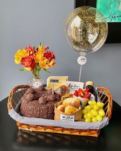 a basket filled with lots of food next to a glass of wine and a balloon