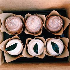 six donuts with white frosting and sprinkles in a cardboard box