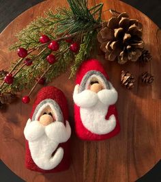 two santa claus slippers sitting on top of a wooden table next to pine cones