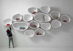 two children playing in front of a white wall with bookshelves and shelves on it