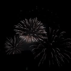 fireworks are lit up in the dark sky above some building's roof tops at night