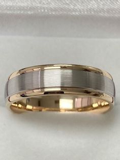 two tone gold and silver wedding ring on white fabric background, close - up view