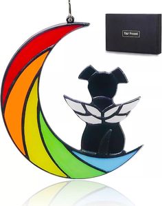 a dog sitting on top of a rainbow moon with a black box in the background