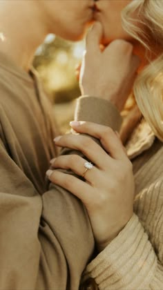 two women are kissing each other with their hands on their chests and one is wearing a ring