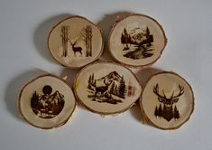 four wood slices with pictures of animals and trees on them are arranged in the shape of coasters