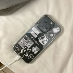 an iphone case with various stickers on it sitting on a white sheet covered bed