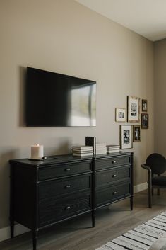 a flat screen tv mounted to the side of a wall next to a black dresser