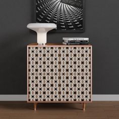 a white vase sitting on top of a wooden cabinet next to a painting and books