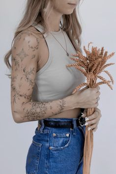 a woman with tattoos holding a plant in her hands