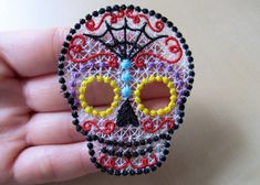 a hand holding a small beaded sugar skull