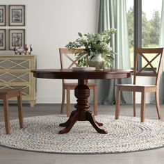 a dining room table with chairs and a rug on the floor in front of it