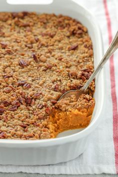 a casserole dish filled with sweet potato casserole and topped with pecans