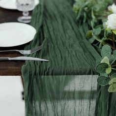 the table is set with silverware and green linens, along with white flowers