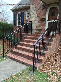 a brick house with black iron railings and stairs