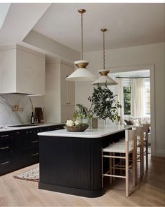 a kitchen with an island and two pendant lights hanging from it's ceiling above the counter