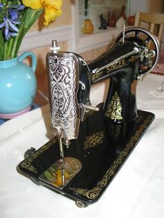 a sewing machine sitting on top of a table next to a vase filled with flowers