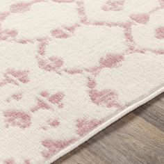 a pink and white rug on the floor with wood floors in the background, close up