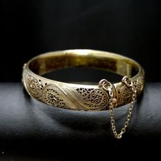 *Description: This is a beautiful Art Nouveau hinged silver bracelet with a gold wash from around the 1920s. It has European origins with stamps for silver and one difficult to read on the clasp. Photo is included. This silver bracelet with a gold wash was tested by me and tested for silver and minimum 10K gold wash or vermeil. The clasp and hinge are in great working order. If you are looking for a wonderful heirloom gift, this would be perfect. This bracelet would be a great addition to your v Antique Gold Bracelet Stamped 14k, Antique 14k Stamped Gold Bracelet, Antique Gold Cuff Bracelet Collectible, Elegant Antique Gold Brass Bracelet, Brass Wedding Bracelet Jewelry, Brass Wedding Bracelet, Elegant Antique Gold Bangle, Brass Bracelet Jewelry For Wedding, Wedding Brass Bracelet Jewelry