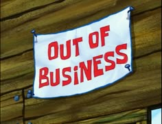 a sign that says out of business hanging from the side of a building on a wooden wall