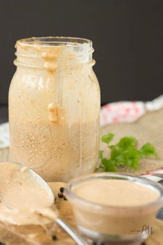 a jar filled with liquid sitting on top of a wooden table next to a spoon