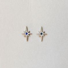 These earrings are a silver version of the beautiful 14k rose gold Polaris Earrings. This sterling silver earring is paired with a blue sapphire center stone which gives it a beautiful antique vibe. Details: Sterling silver stud measures about 11.16 x 7.8mm Blue Sapphires measure about 1.6mmSOLD AS A PAIR Free Shipping on Domestic Orders Materials: sterling silver, sapphire, blue sapphire Silver Celestial Gemstone Earrings, Silver Sapphire Earrings With Gemstones, Sterling Silver Sapphire Gemstone Earrings, Celestial White Gold Sterling Silver Earrings, Sterling Silver Celestial Earrings For Gift, Blue Sterling Silver Earrings With Polished Finish, White Gold Sterling Silver Birthstone Earrings, Celestial Sapphire Sterling Silver Jewelry, Celestial Style Sapphire Jewelry In Sterling Silver