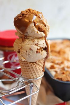 three scoops of ice cream in a waffle cone with caramel drizzle on top